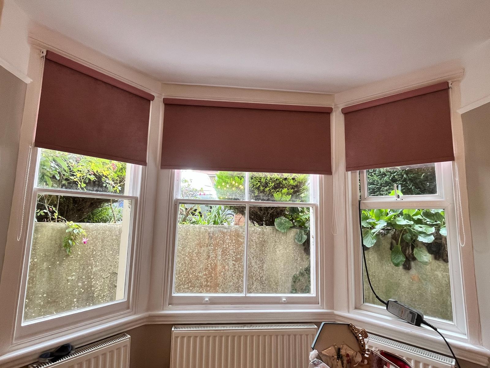 Pink roller blinds on a bay window